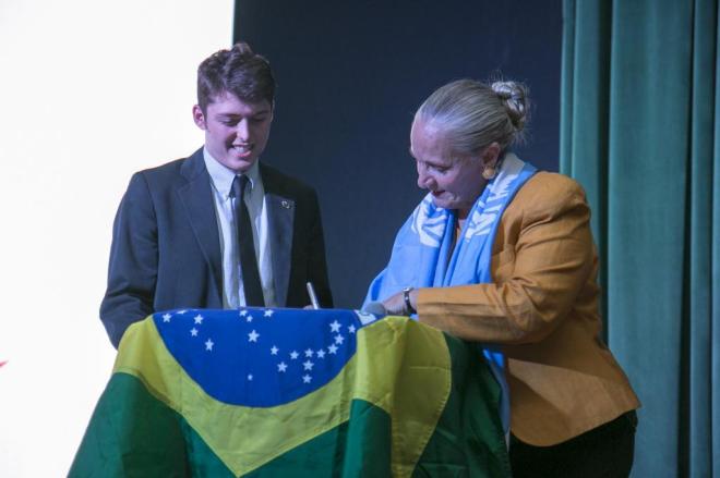 Foto com Israel Rocha juntamente com a fundadora e presidente da organização Youth for Human Rights International no Brasil (YHRI), Mary Shuttleworth. Mary está assinando a bandeira do Brasil.